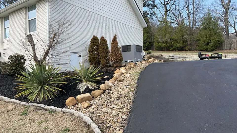Finished driveway with landscaped stone beds beside a home