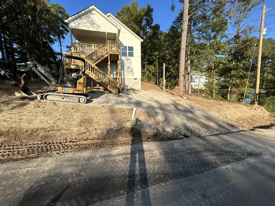 Mini excavator grading the slope beside a new home