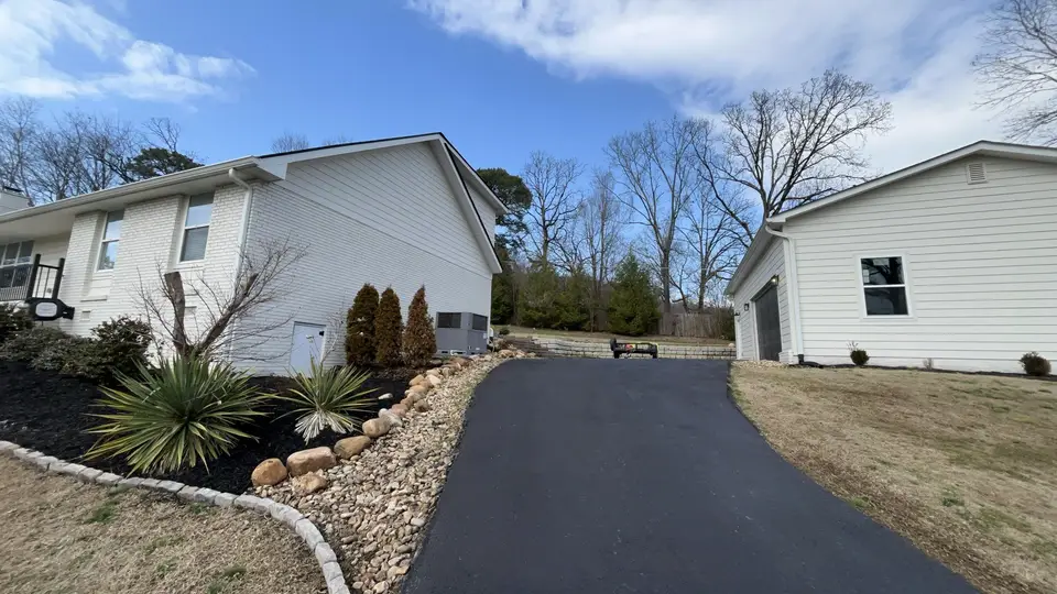 Finished driveway with landscaped stone beds beside a home